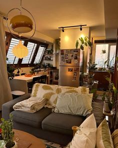 a living room filled with furniture next to a window and a refrigerator freezer covered in plants