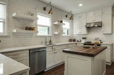 a large kitchen with white cabinets and wood counter tops, along with stainless steel appliances