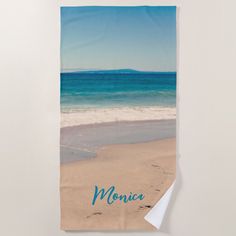 a beach towel with the name monica written on it and an ocean view in the background