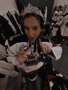 a woman in a hockey uniform giving the peace sign with her hand and wearing a tiara