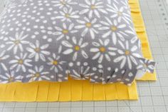 a close up of a bed with yellow and gray sheets on it, next to a ruler