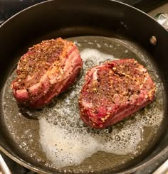 two steaks are being cooked in a frying pan with oil on the stove