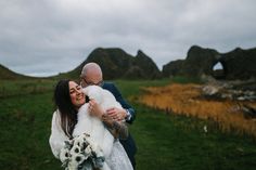 a man and woman hugging each other in the grass