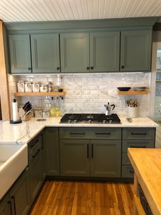 a kitchen with green cabinets and white counter tops, wood flooring and wooden counters