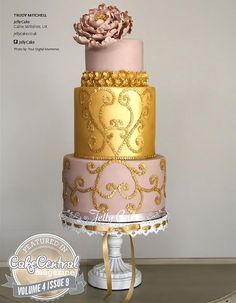 a three tiered cake with gold and pink frosting on the top, topped with a large flower