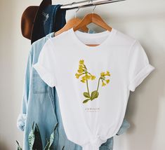 Cowslip T-Shirt. 100% Organic Cotton, Woman/Ladies Fit, S - 2XL, , Yellow Flower T-Shirt. Botanical T-Shirt, Floral T-Shirt. This lovely Cowslip t-shirt features an original illustration by British artist Rosemary Fugeman, founder of Britain Illustrated. DETAILS * Womens sizes small - 2XL * Fully sustainable 100% organic cotton * Fair wear, fair trade approved * Fabric weight: 4.57 oz/yd² (155 g/m²) COLOUR * White Enquries If you have any questions please get in touch with us here at the studio. Wildflower Shirt, Illustration Botanique, Botanical Shirt, Mothers Day T Shirts, No Rain, Valentines Day Gifts For Her, Flower Shirt, Mothers Day Shirts, Valentines Day Shirts