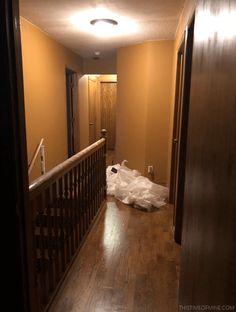 an empty hallway with wood flooring and white plastic bag on the ground in front of it