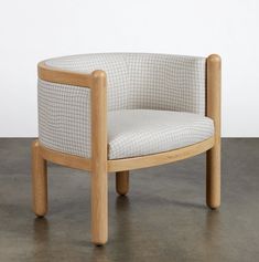 a wooden chair sitting on top of a cement floor next to a white and black wall