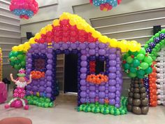 an inflatable house made out of balloons with a girl on the front porch