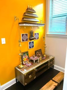 a wooden bench sitting in front of a yellow wall with pictures hanging on the wall