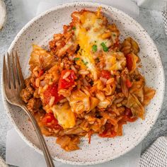 a white plate topped with lasagna covered in cheese and sauce next to a fork