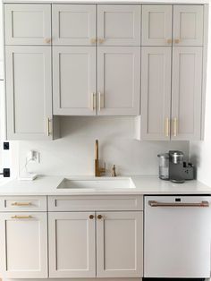 a kitchen with white cabinets and gold hardware on the handles, sink and dishwasher