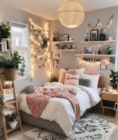 a bedroom decorated in pink and grey with lights on the wall above the bed, rugs and pillows