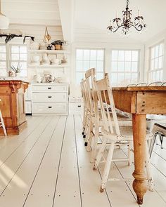 an old fashioned kitchen with white floors and wooden furniture in the center, along with chandelier