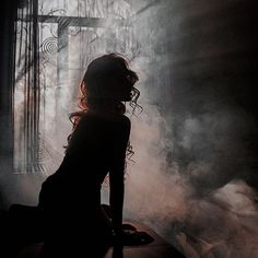 a woman sitting in front of a window with steam coming out of her body and head