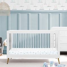 a baby's room with blue walls and white furniture