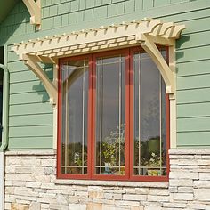 a green house with a red door and white window trim on the side of it