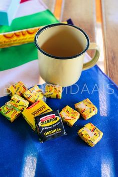 a cup of tea and some candy on a blue table cloth next to other candies