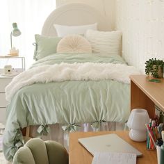 a bedroom with a bed, desk and laptop on the table in front of it