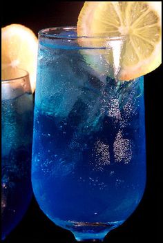 two glasses filled with blue liquid and lemon wedges