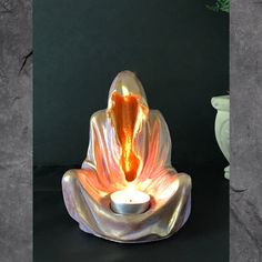 a candle that is in the shape of a buddha's head with an orange flower on it