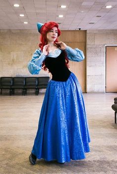 a woman in a blue dress is posing for the camera with her hands on her hips