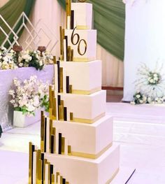 a tall white and gold wedding cake with the number sixty on it's side