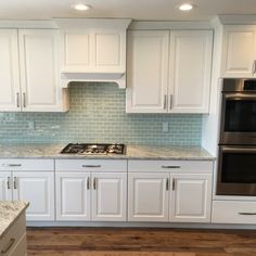 a kitchen with white cabinets and marble counter tops