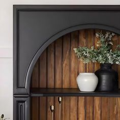 two vases are sitting on a shelf in front of a wood paneled wall