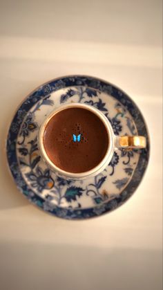 a cup of hot chocolate on a blue and white saucer with a butterfly decoration