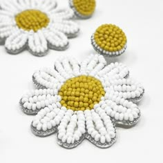 three white and yellow flowers are shown on a white surface with one flower in the center