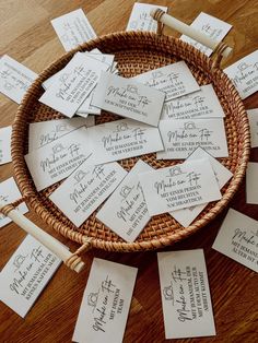 a wicker basket filled with lots of place cards on top of a wooden table