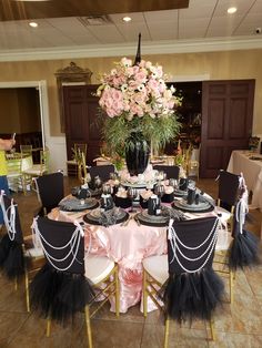 a table set up with black and pink decorations for a formal function at a wedding