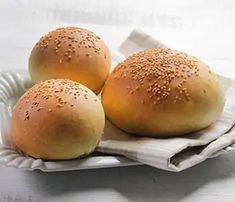 three buns with sesame seeds sit on a paper plate