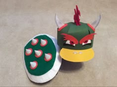 two paper masks with horns and claws on them, one is green and the other is red