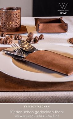 a white plate topped with a knife and fork next to a brown napkin on top of a table