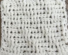 a white crocheted blanket sitting on top of a wooden floor