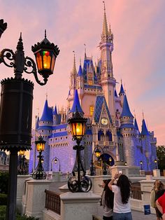 a woman taking a photo in front of a castle at dusk with her cell phone