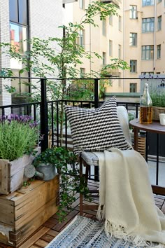 the balcony is decorated with potted plants and other outdoor furniture, including a chair that has a black and white checkered pillow on it