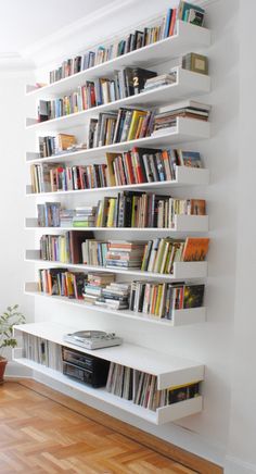 a bookshelf filled with lots of books on top of a hard wood floor