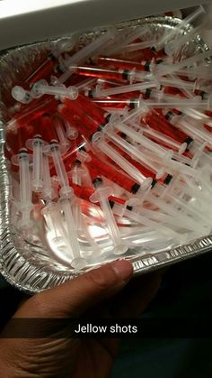 a person holding a tray full of red and white toothbrushes in plastic wrappers