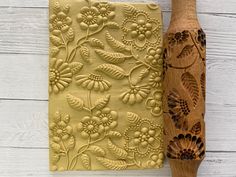 a wooden vase next to a carved piece of wood with flowers on it and a flowery design