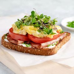 a close up of a sandwich with tomatoes and other food items on top of it