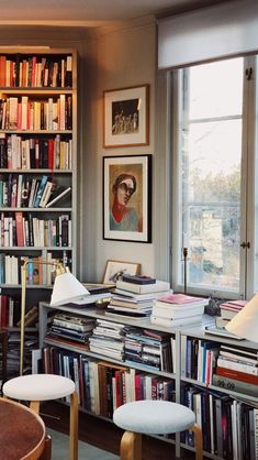 a room filled with lots of books next to a window and a chair in front of it