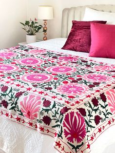 a bed with pink and red pillows on top of it