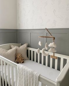 a white crib with a teddy bear and some pillows on it's side