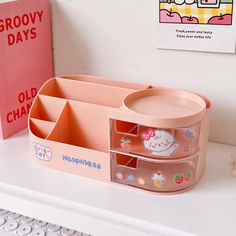 there is a pink box with stickers in it on the shelf next to a book