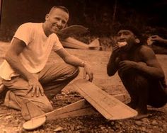 two men sitting on the ground next to each other and one is holding a bat