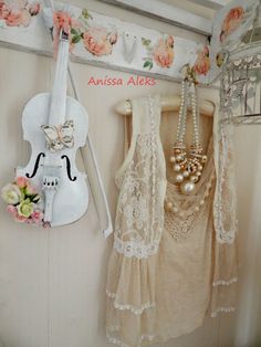 there is a violin hanging on the wall next to some clothing and necklaces in this room