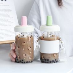 two small jars filled with liquid sitting on top of a white table next to each other